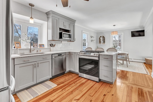 kitchen with gray cabinetry, kitchen peninsula, pendant lighting, stainless steel appliances, and decorative backsplash