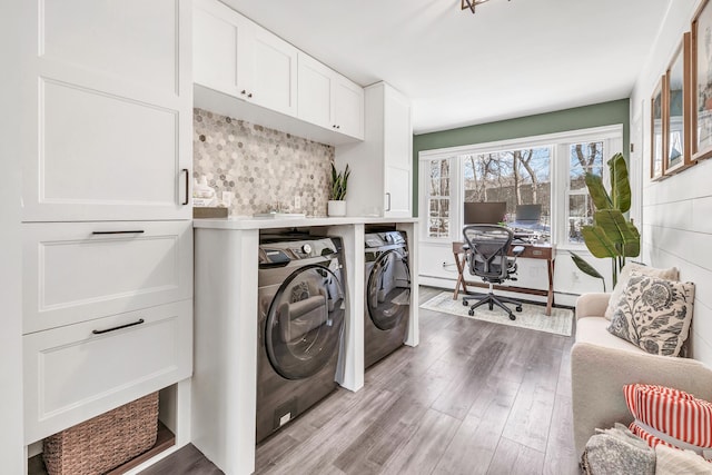 laundry room featuring a baseboard radiator, washing machine and dryer, cabinets, and light wood-type flooring