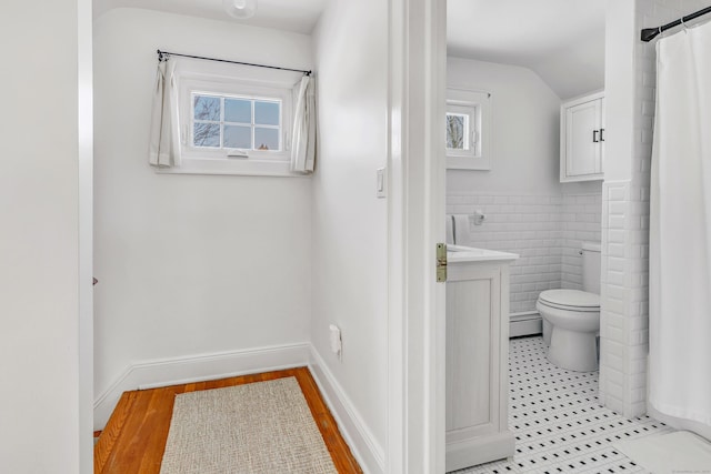 bathroom featuring lofted ceiling, hardwood / wood-style flooring, tile walls, vanity, and toilet