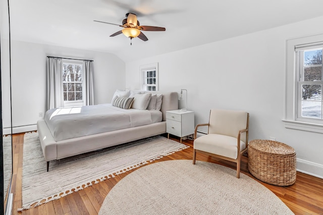 bedroom featuring hardwood / wood-style flooring, ceiling fan, a baseboard radiator, and multiple windows