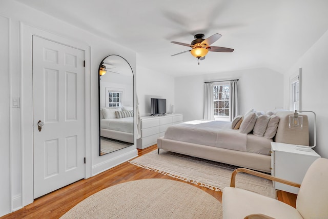 bedroom with ceiling fan, wood-type flooring, and lofted ceiling