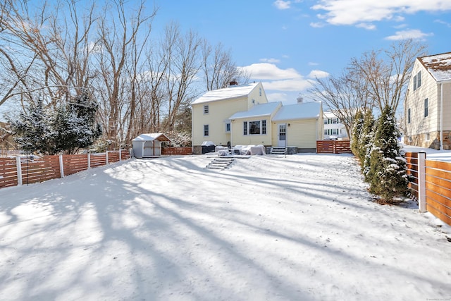 snow covered rear of property with a storage shed