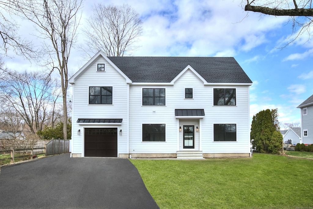 view of front of home with a standing seam roof, an attached garage, metal roof, fence, and driveway