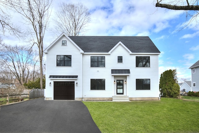 view of front of home with a standing seam roof, an attached garage, metal roof, fence, and driveway