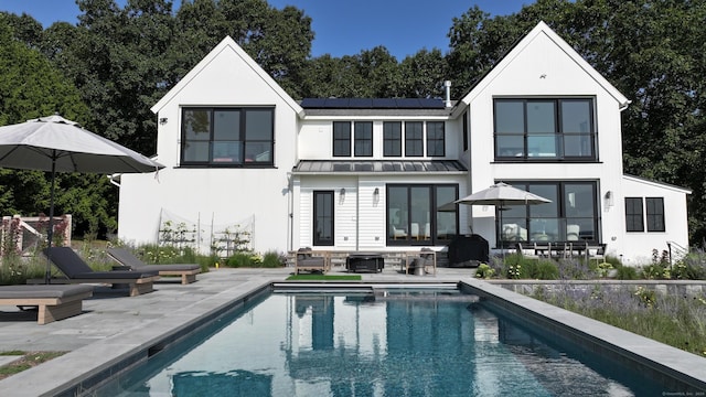 rear view of house with a patio and solar panels