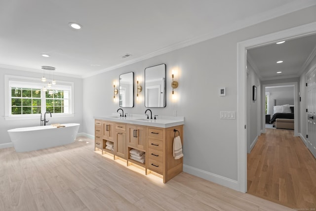 bathroom with ornamental molding, wood-type flooring, a bath, and vanity