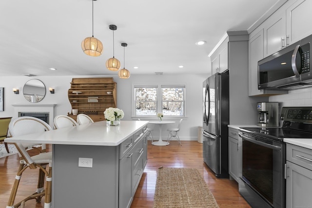 kitchen featuring appliances with stainless steel finishes, gray cabinets, a breakfast bar, and a kitchen island