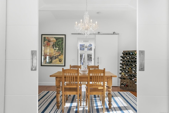 dining space featuring a barn door, hardwood / wood-style floors, and a notable chandelier