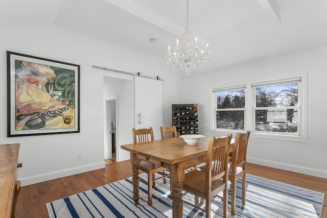 dining room with a barn door, a chandelier, and dark hardwood / wood-style flooring