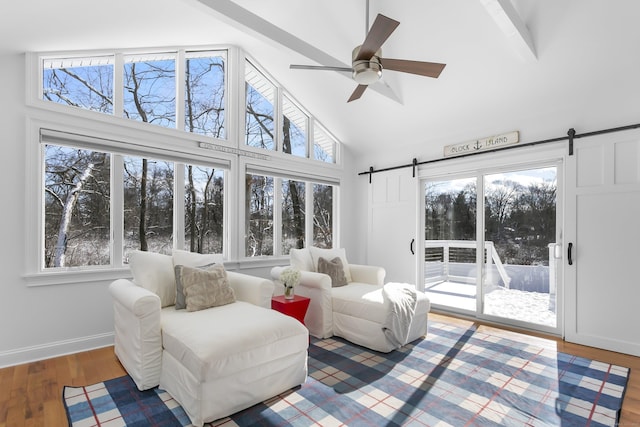 sunroom / solarium with ceiling fan, a barn door, and lofted ceiling with beams