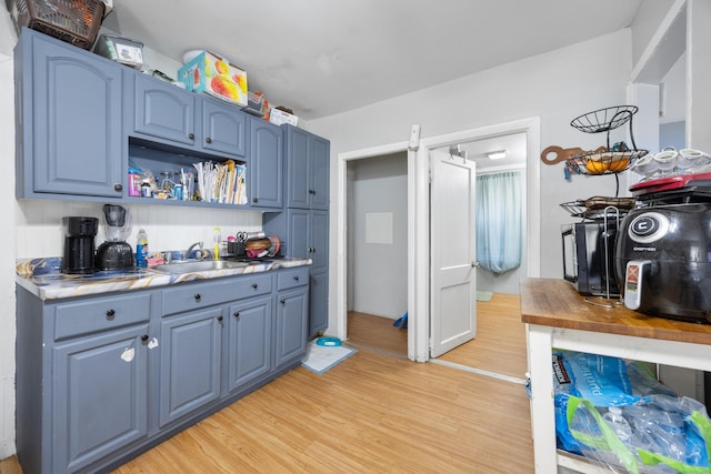 kitchen featuring sink, blue cabinets, and light hardwood / wood-style flooring