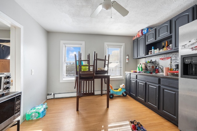 kitchen featuring ceiling fan, sink, a textured ceiling, light hardwood / wood-style floors, and stainless steel appliances