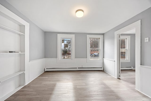 spare room with a baseboard radiator and light wood-type flooring