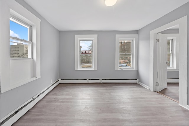 empty room featuring light hardwood / wood-style floors and a baseboard heating unit