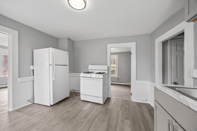 kitchen featuring white appliances, a wealth of natural light, a baseboard heating unit, and light hardwood / wood-style floors