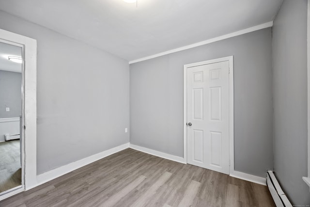 unfurnished room with light wood-type flooring, crown molding, and baseboard heating