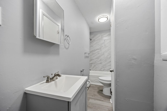 full bathroom featuring toilet, a textured ceiling, wood-type flooring, vanity, and shower / washtub combination