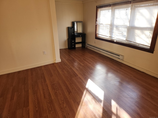 spare room featuring baseboard heating and dark hardwood / wood-style flooring