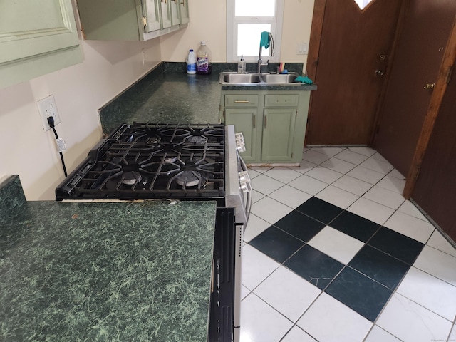 kitchen featuring green cabinets, light tile patterned floors, stainless steel gas stove, and sink