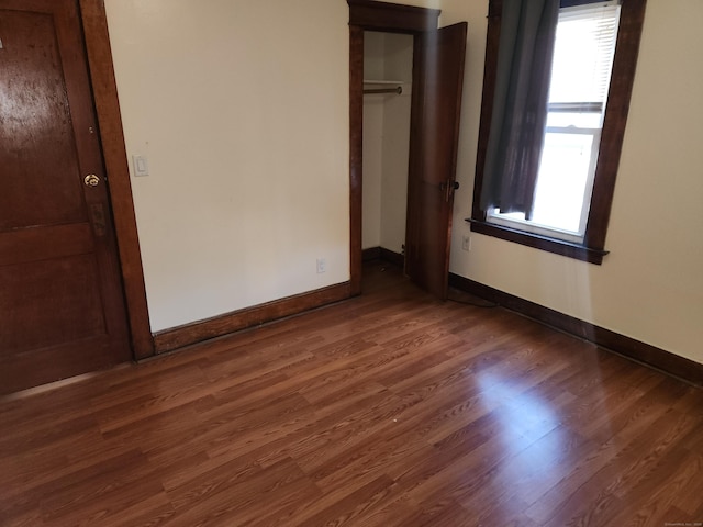 unfurnished bedroom with dark hardwood / wood-style floors and a closet