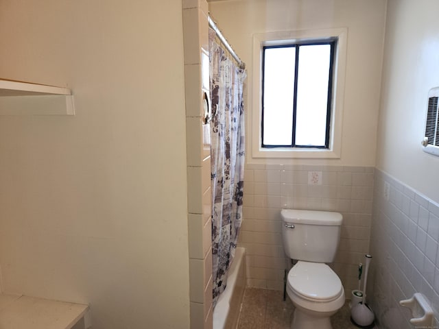 bathroom with toilet, tile walls, and shower / bath combination with curtain