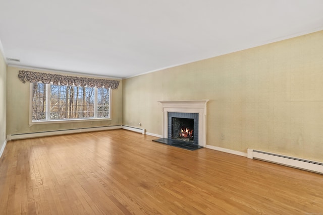 unfurnished living room featuring a fireplace, a baseboard radiator, and light hardwood / wood-style floors