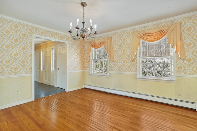 empty room featuring hardwood / wood-style flooring, ornamental molding, a baseboard heating unit, and a chandelier