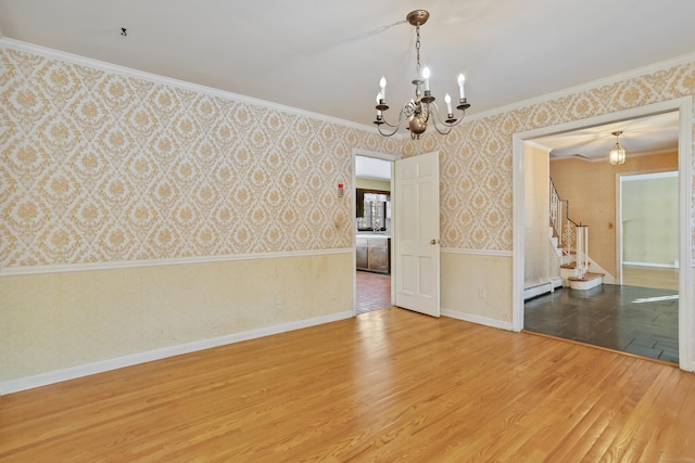 spare room featuring wood-type flooring, an inviting chandelier, crown molding, and baseboard heating