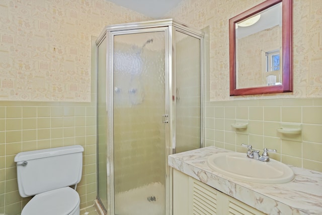 bathroom featuring an enclosed shower, vanity, tile walls, and toilet