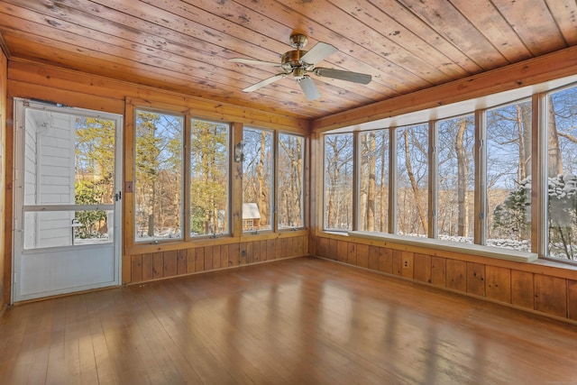 unfurnished sunroom featuring wood ceiling, a wealth of natural light, and ceiling fan