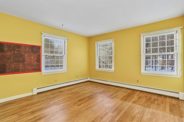 unfurnished room featuring a baseboard heating unit and light hardwood / wood-style flooring