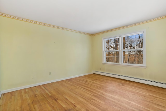 empty room featuring a baseboard heating unit and light wood-type flooring