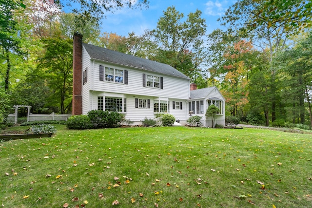 rear view of house featuring a sunroom and a lawn