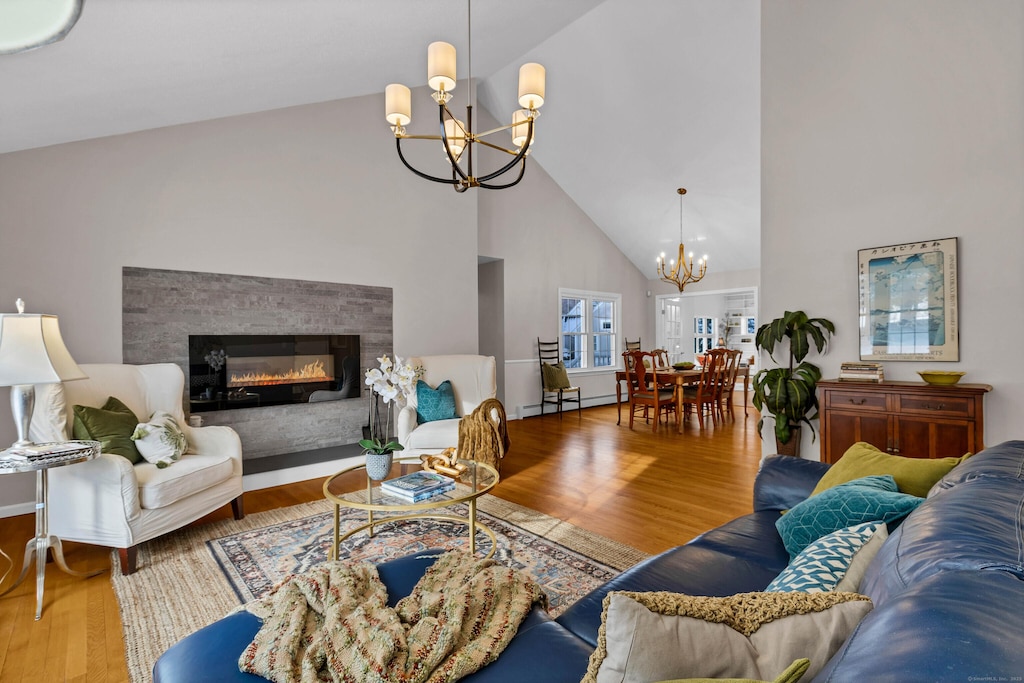 living room with high vaulted ceiling, an inviting chandelier, hardwood / wood-style floors, and a baseboard radiator