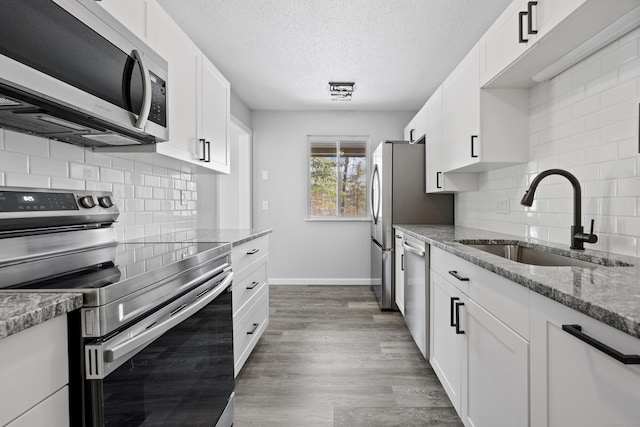 kitchen featuring sink, white cabinetry, light stone countertops, and appliances with stainless steel finishes