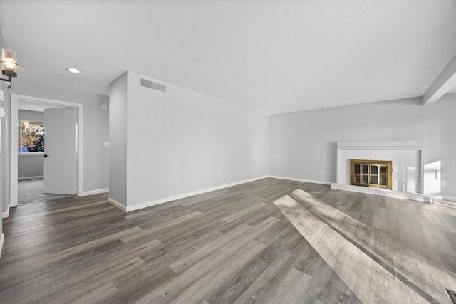 unfurnished living room featuring a brick fireplace and dark wood-type flooring