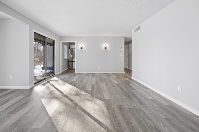 unfurnished living room featuring light hardwood / wood-style floors and a textured ceiling