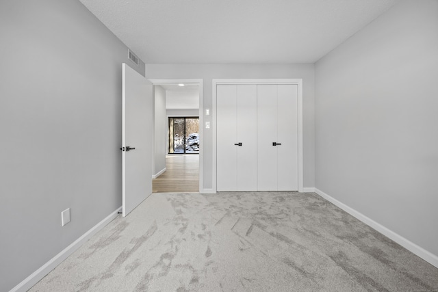 unfurnished bedroom featuring a closet and light carpet