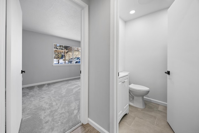 bathroom with a textured ceiling, toilet, and vanity