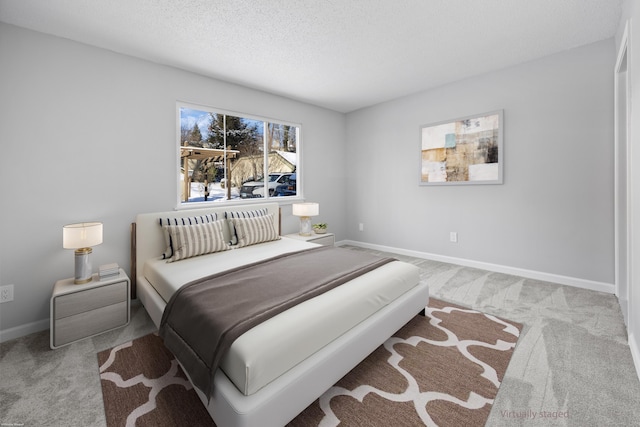 bedroom with light colored carpet and a textured ceiling