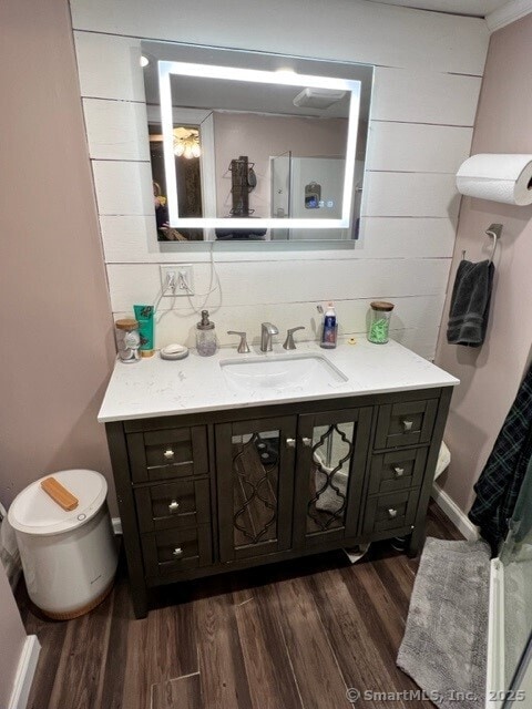 bathroom with hardwood / wood-style flooring, vanity, and wood walls