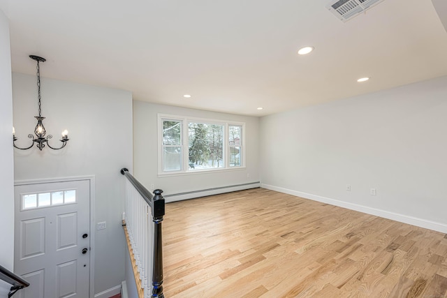 foyer with baseboard heating, light hardwood / wood-style flooring, and a notable chandelier