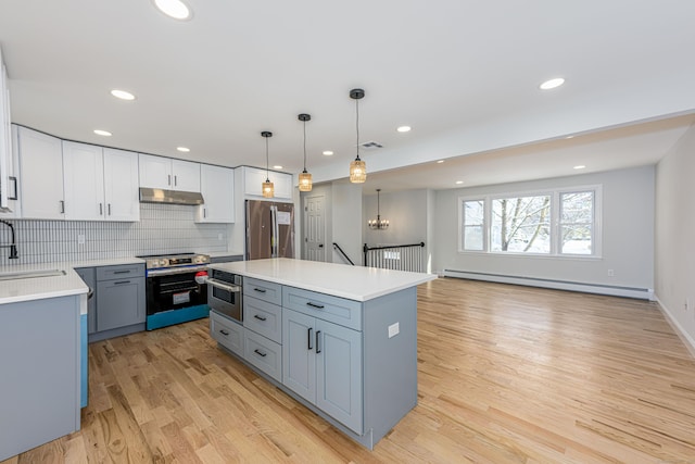 kitchen featuring a center island, a baseboard radiator, white cabinets, decorative light fixtures, and stainless steel appliances