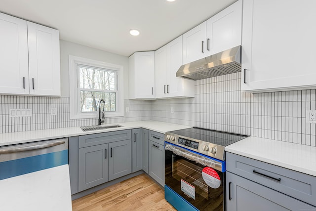 kitchen featuring white cabinetry, stainless steel appliances, sink, gray cabinets, and light wood-type flooring