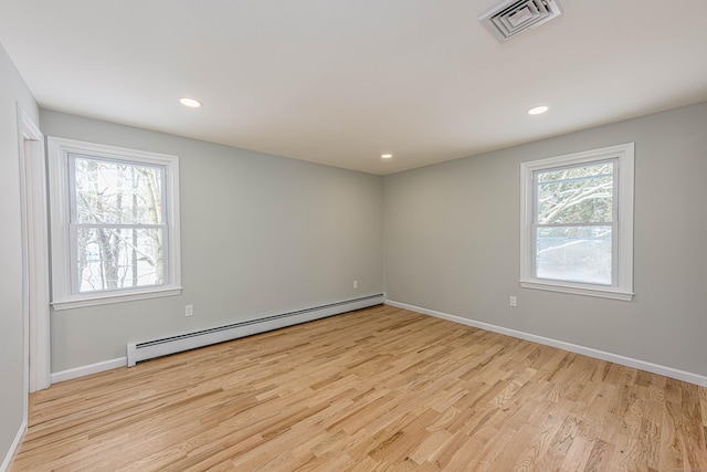 spare room with light hardwood / wood-style floors, plenty of natural light, and a baseboard heating unit