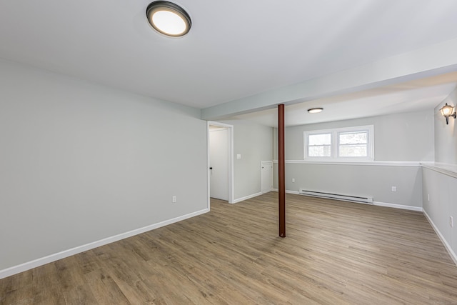 basement featuring a baseboard heating unit and light hardwood / wood-style flooring