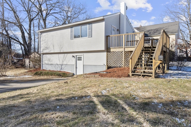 back of property featuring a lawn and a wooden deck