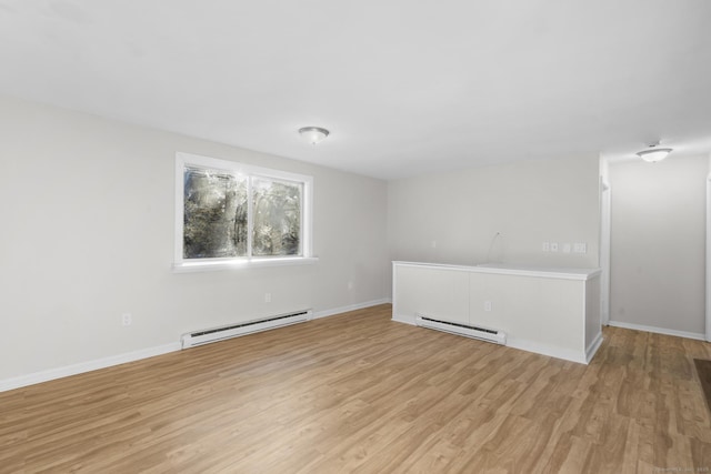 spare room featuring a baseboard heating unit and light hardwood / wood-style flooring