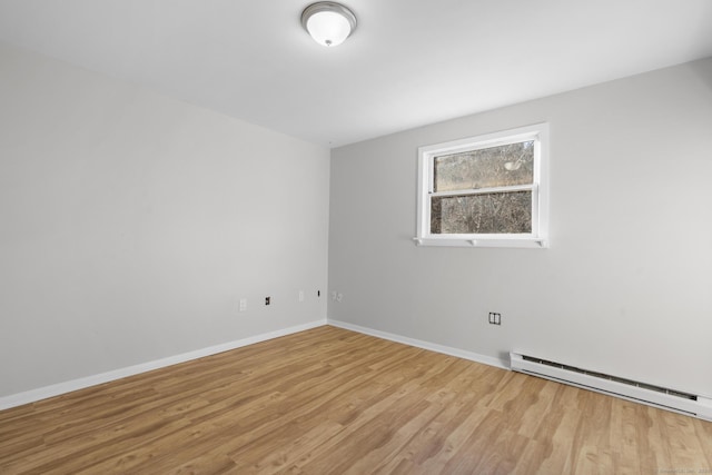 spare room with baseboard heating and light wood-type flooring