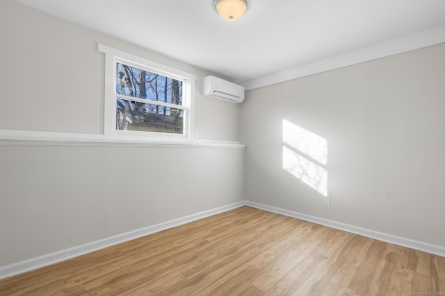 empty room with light wood-type flooring and a wall mounted air conditioner